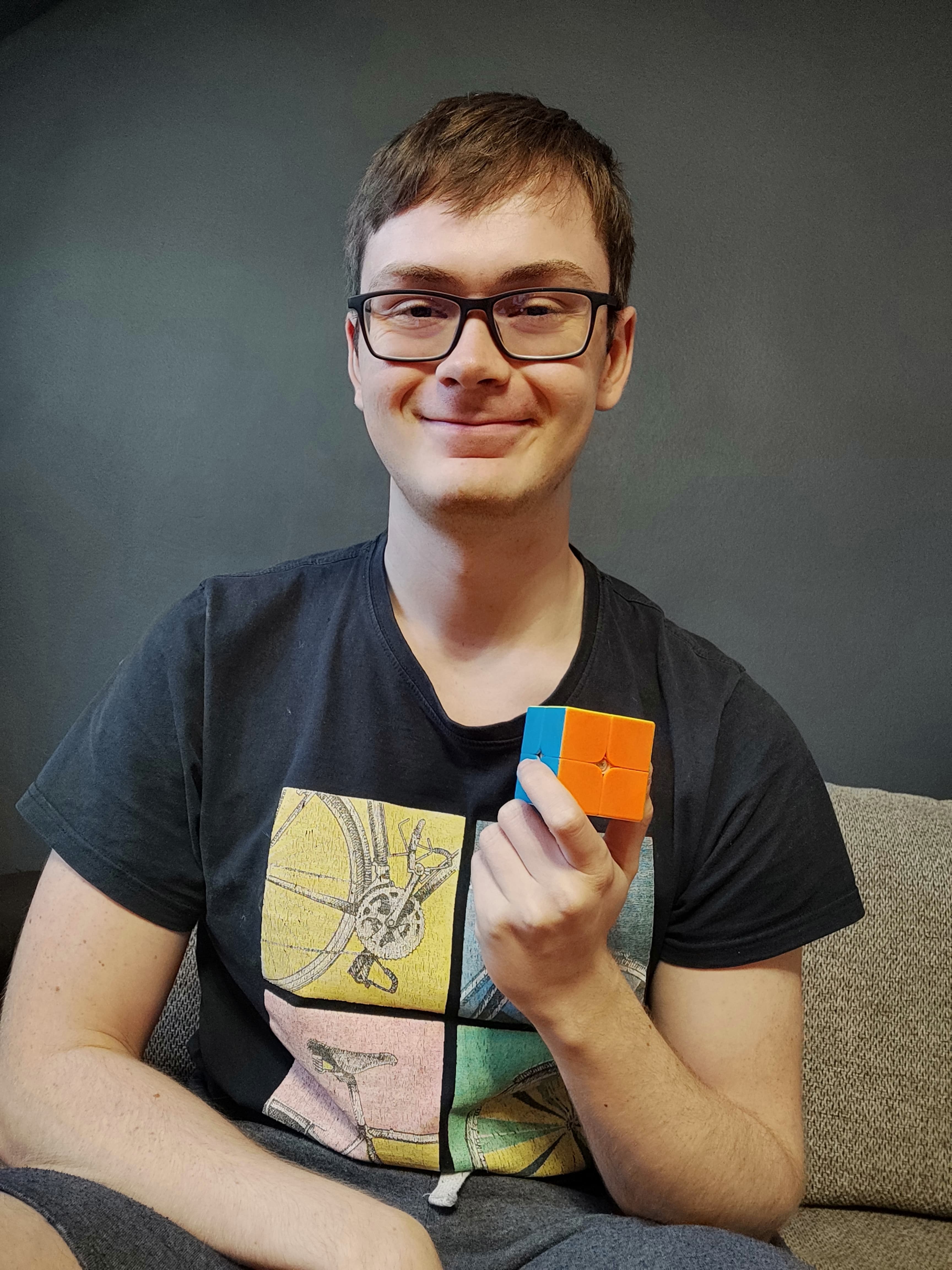 Mężczyzna trzyma w ręcę ułożoną kostkę 2x2.