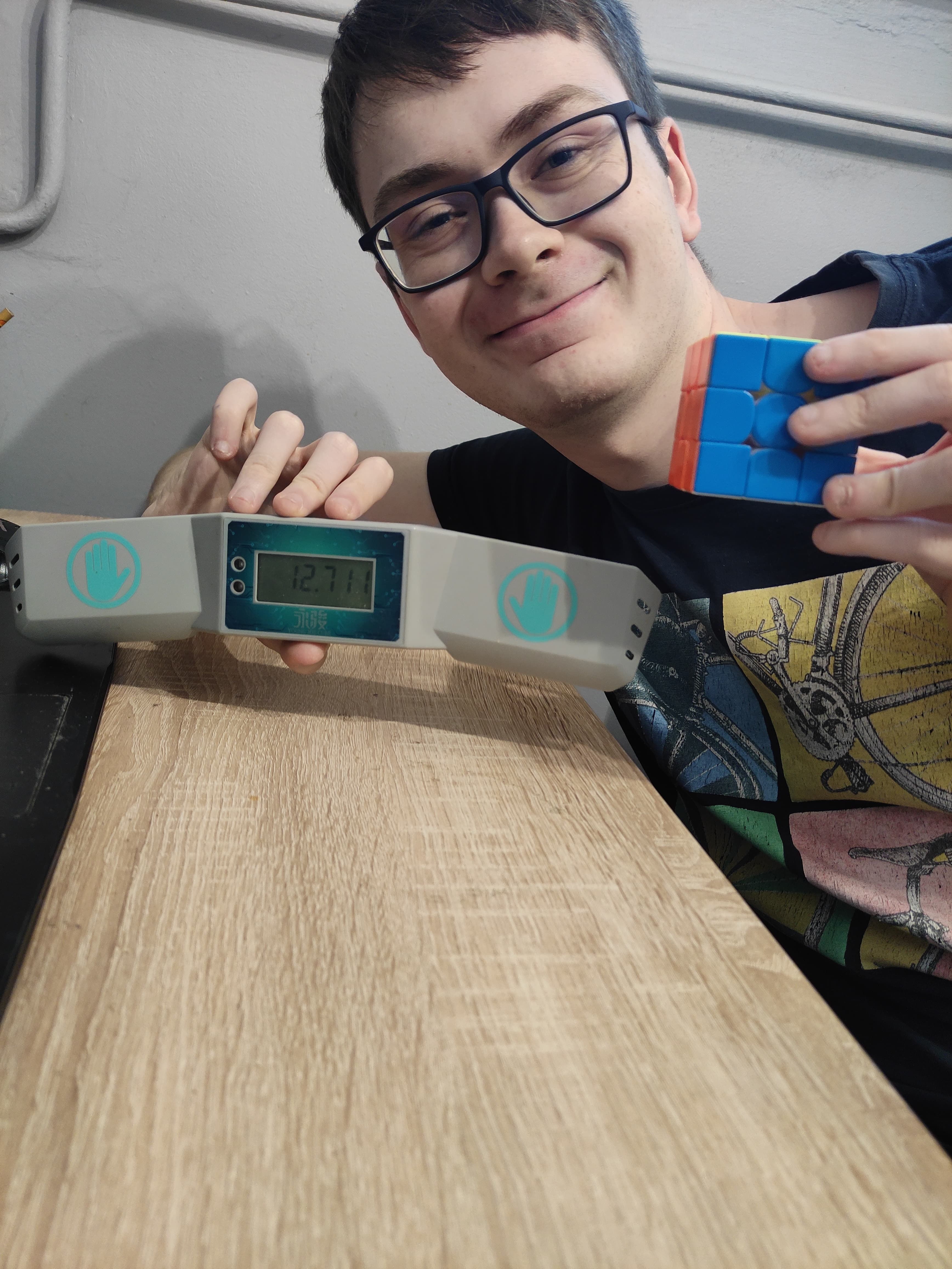 Mężczyzna układający kostkę Rubika metodą Fridrich. W ręku trzyma ułożoną kostkę Rubika, a w drugiej czasomierz do speedcubingu.